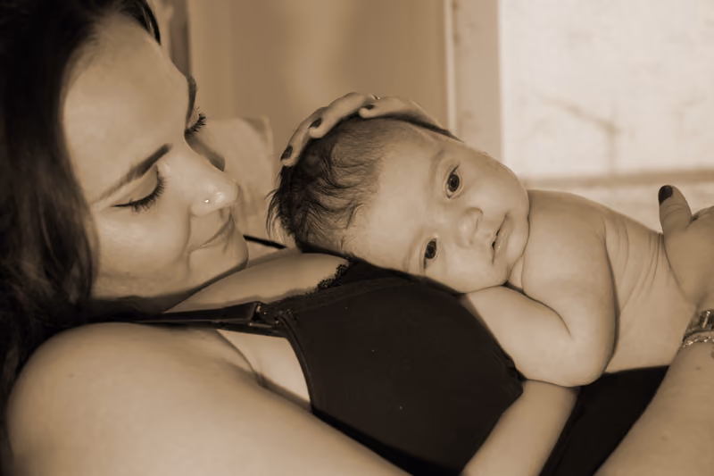 Baby liegt an der Schulter seiner Mutter, in Sepia