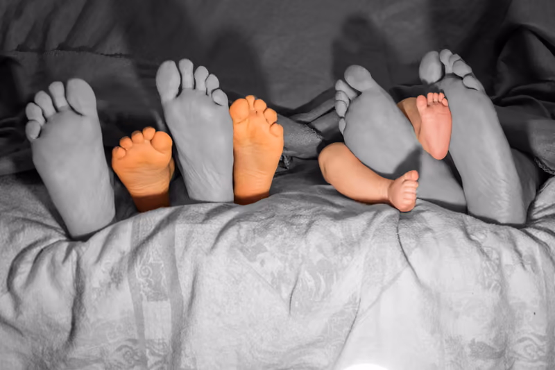 Füße einer Familie in Schwarzweiß, nur die Babyfüße sind farbig