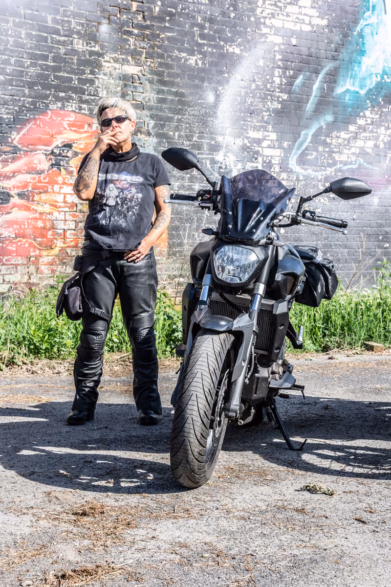 Motorradfahrer neben seiner Maschine vor einer Graffitiwand